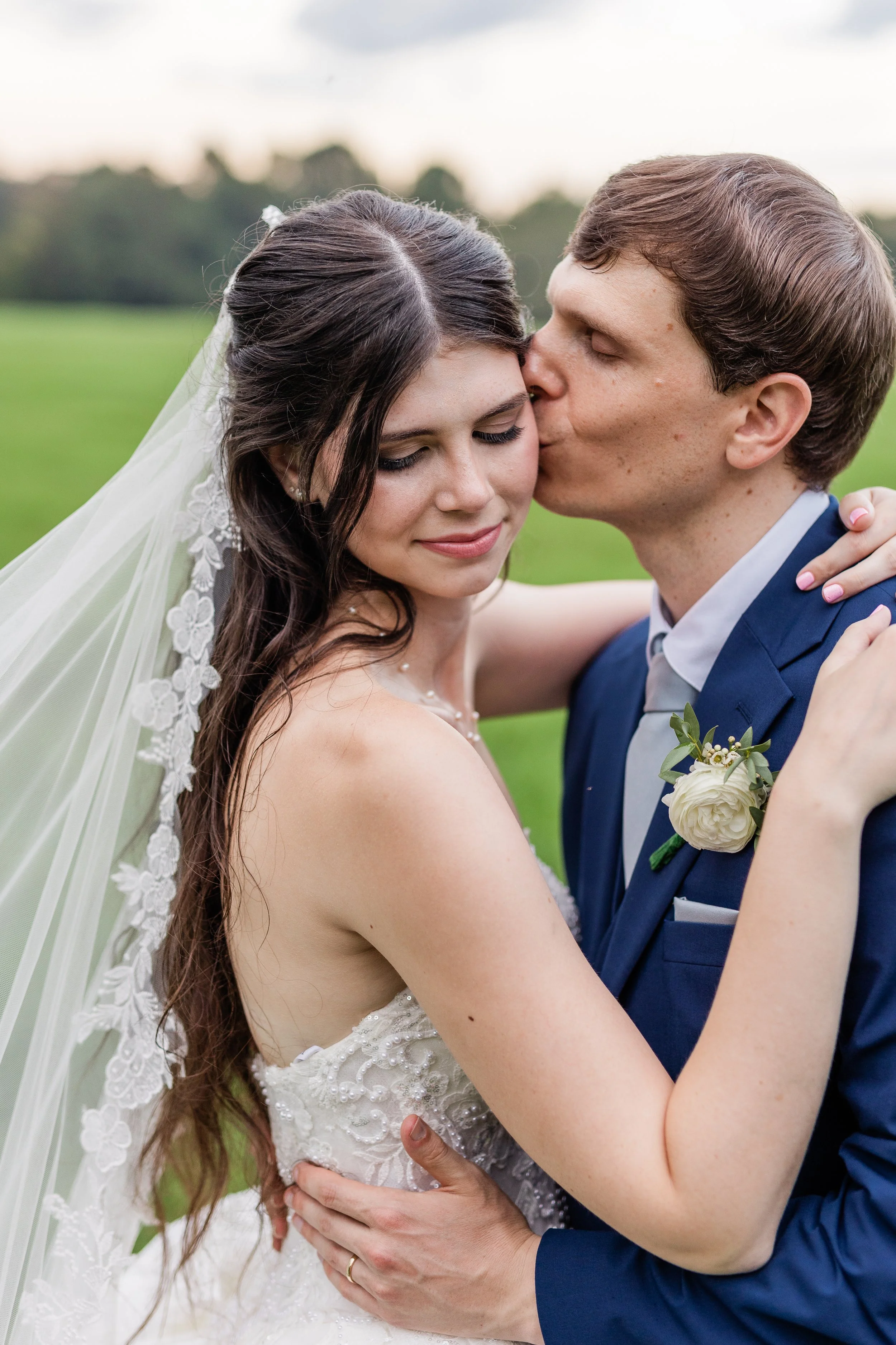 Newlyweds kissing outdoors, bridal hair and makeup by Briar & Bleu