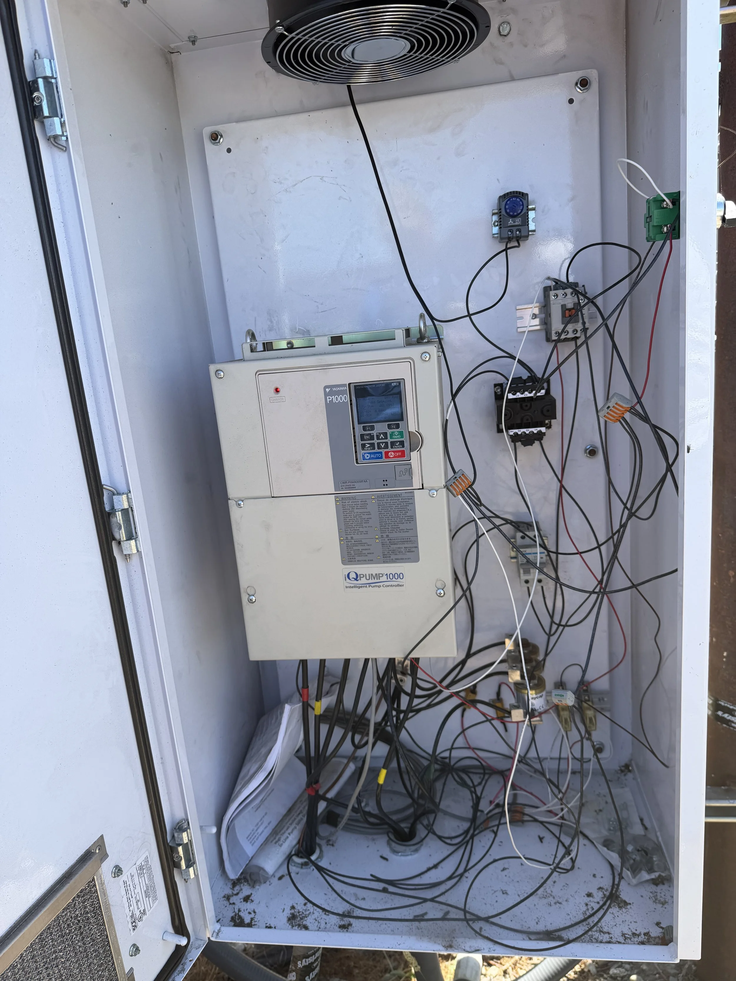 Electrical or control panel box with wires, circuit boards, and a digital control device inside. The panel is open with wires hanging loosely inside.