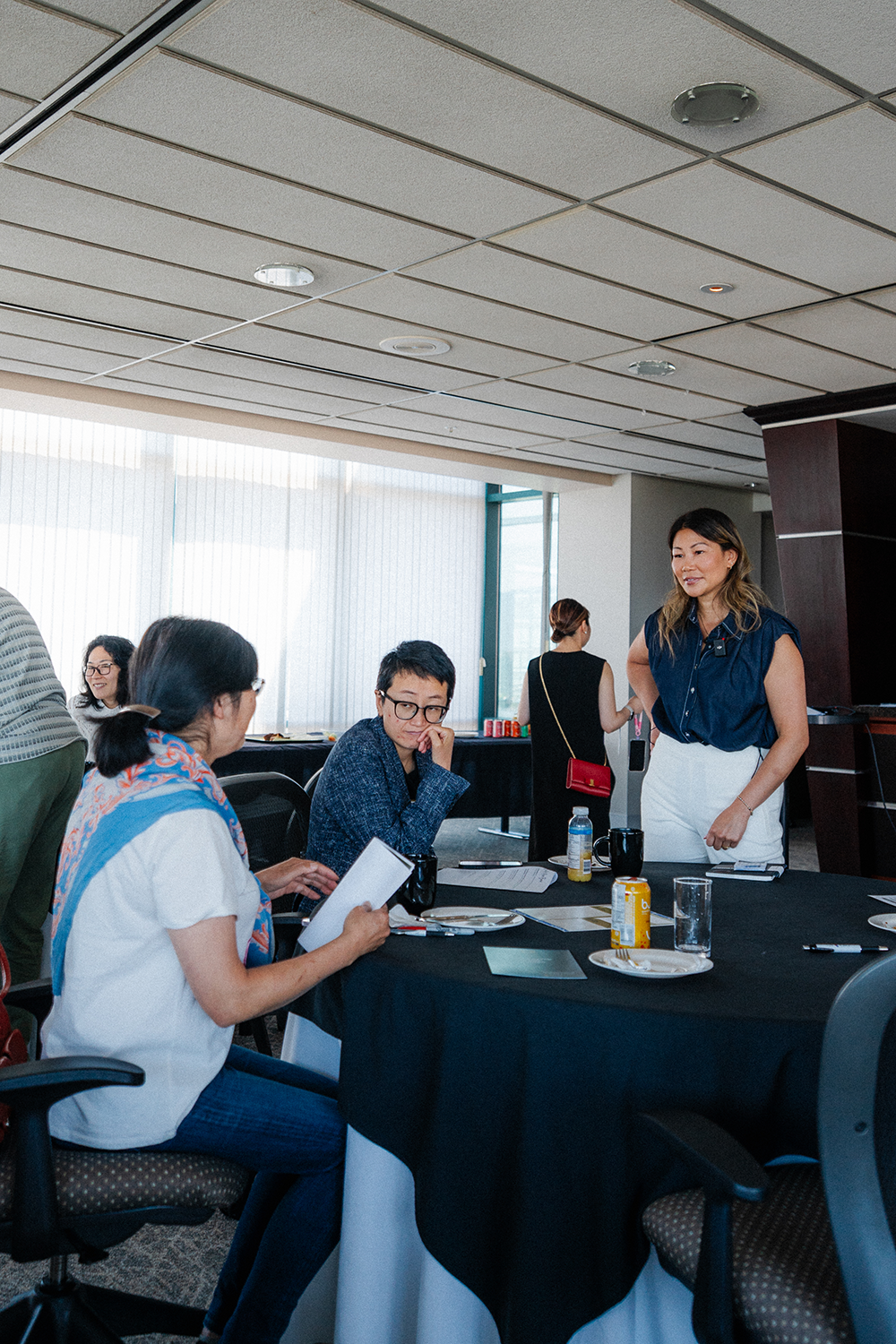Women engaging in a conversation at a roundtable during a professional event in a modern conference room.
