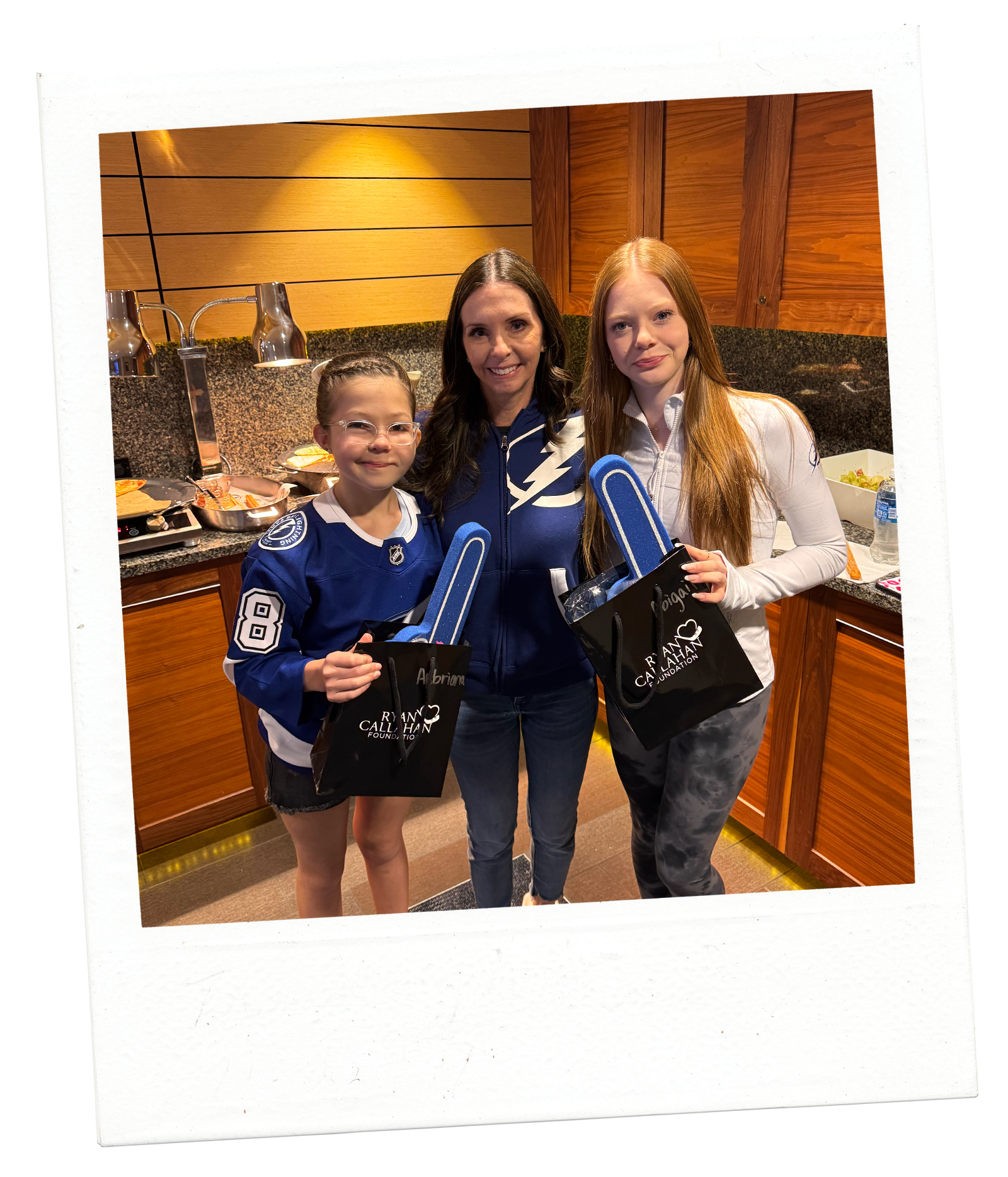 woman and two daughters posing with foam fingers at hockey game suite event