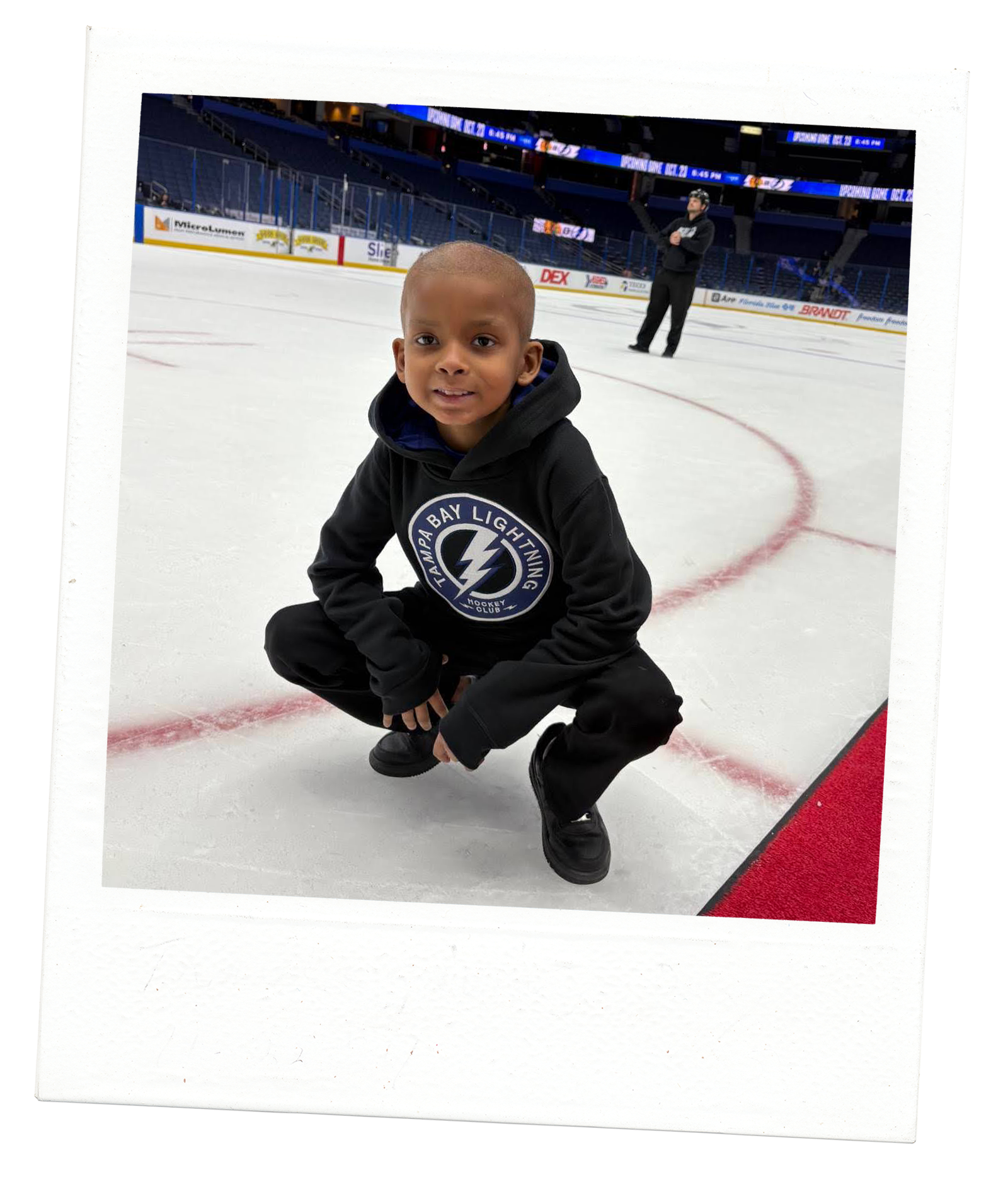 young boy posing on the ice at a stadium hockey game wearing Tampa Bay Lightning hoodie