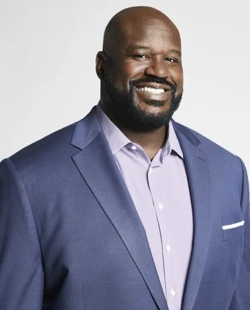 A smiling man in a blue blazer and light purple dress shirt posing for a photo.