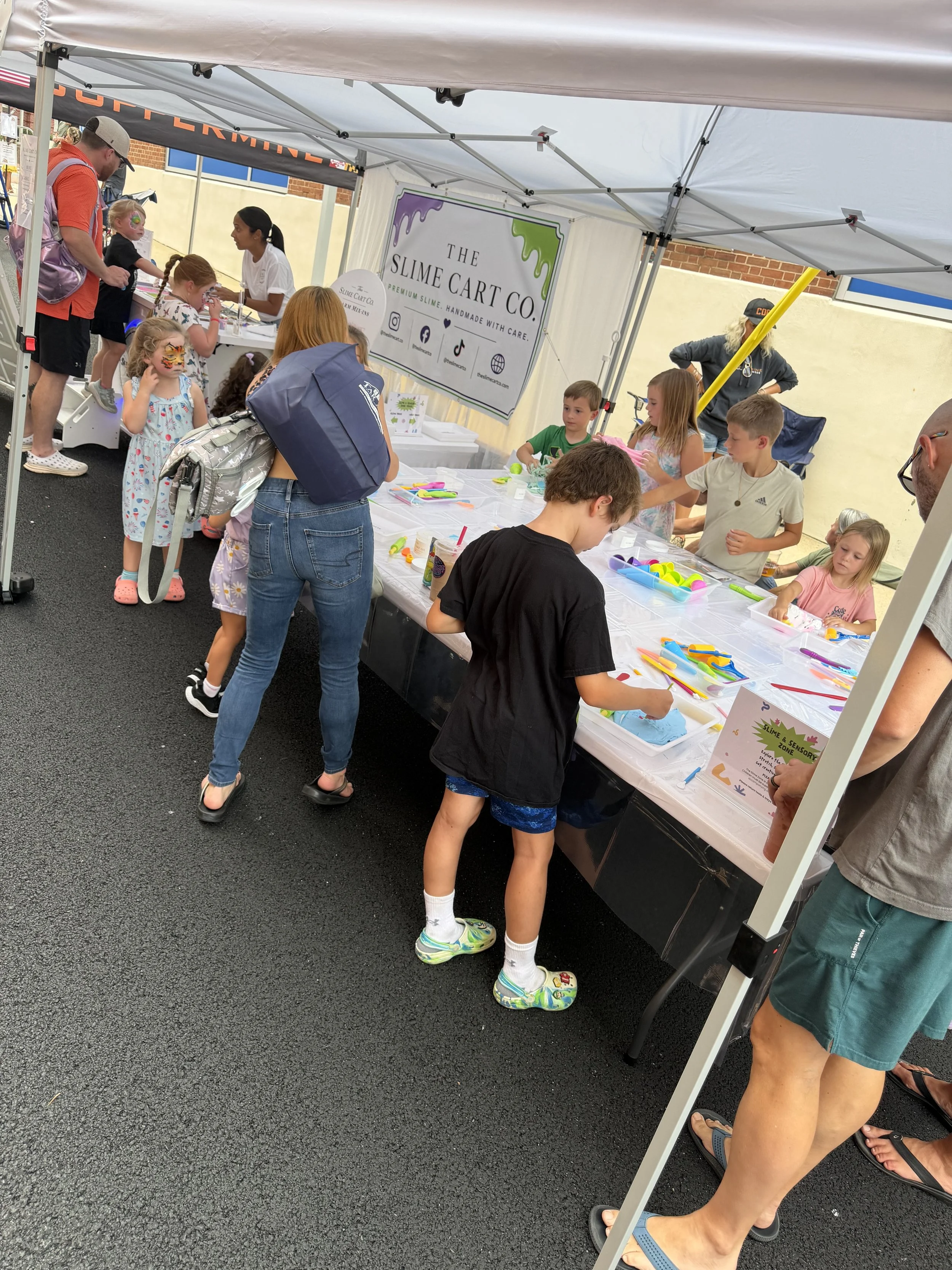Children gathered around The Slime Cart Co. slime zone station.