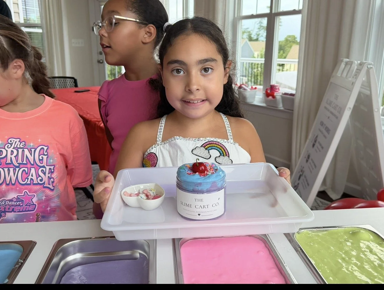 A child creating slime at The Slime Cart Co. station.