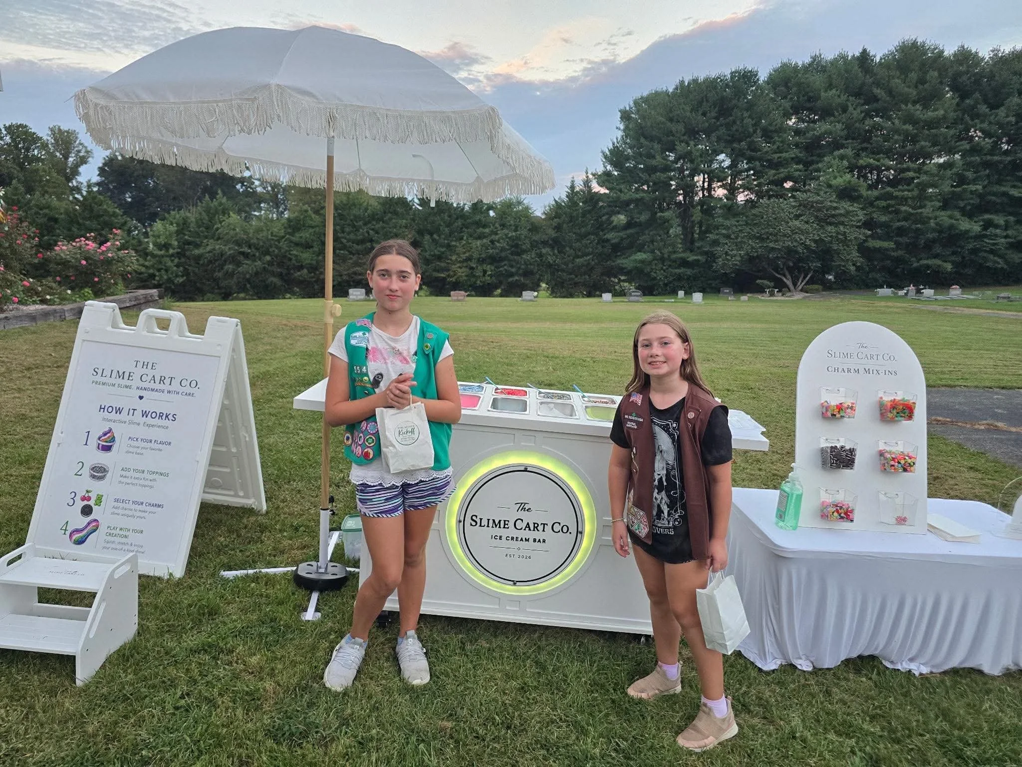 two children standing in front of the slime cart at an outdoor event