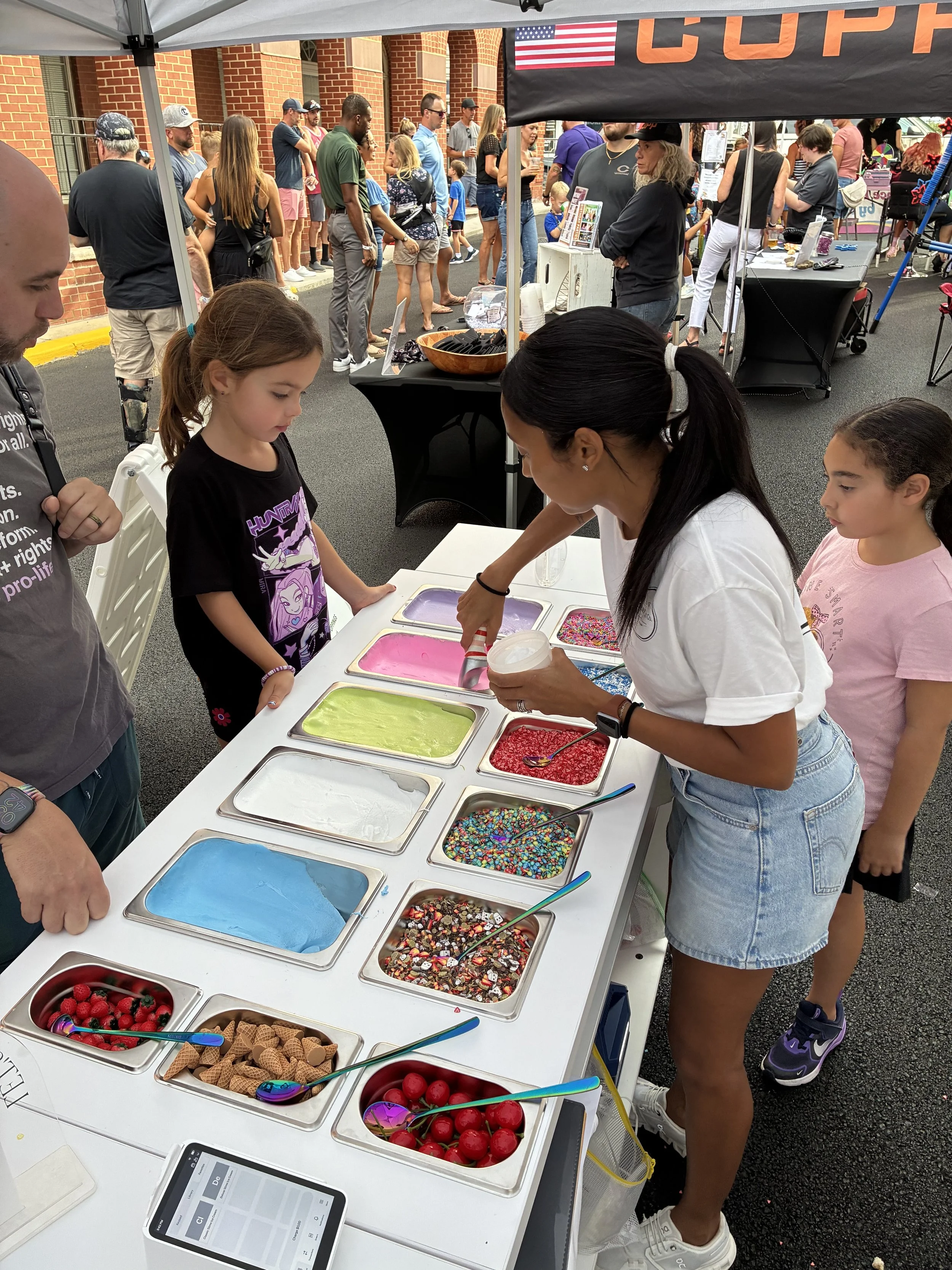  A child and father selecting slime color at the slime cart at an outdoor event.