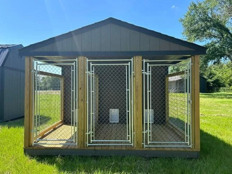 A wooden outdoor dog kennel with three sections, each enclosed with wire fencing and a gated entrance, situated on a grassy lawn under a blue sky.
