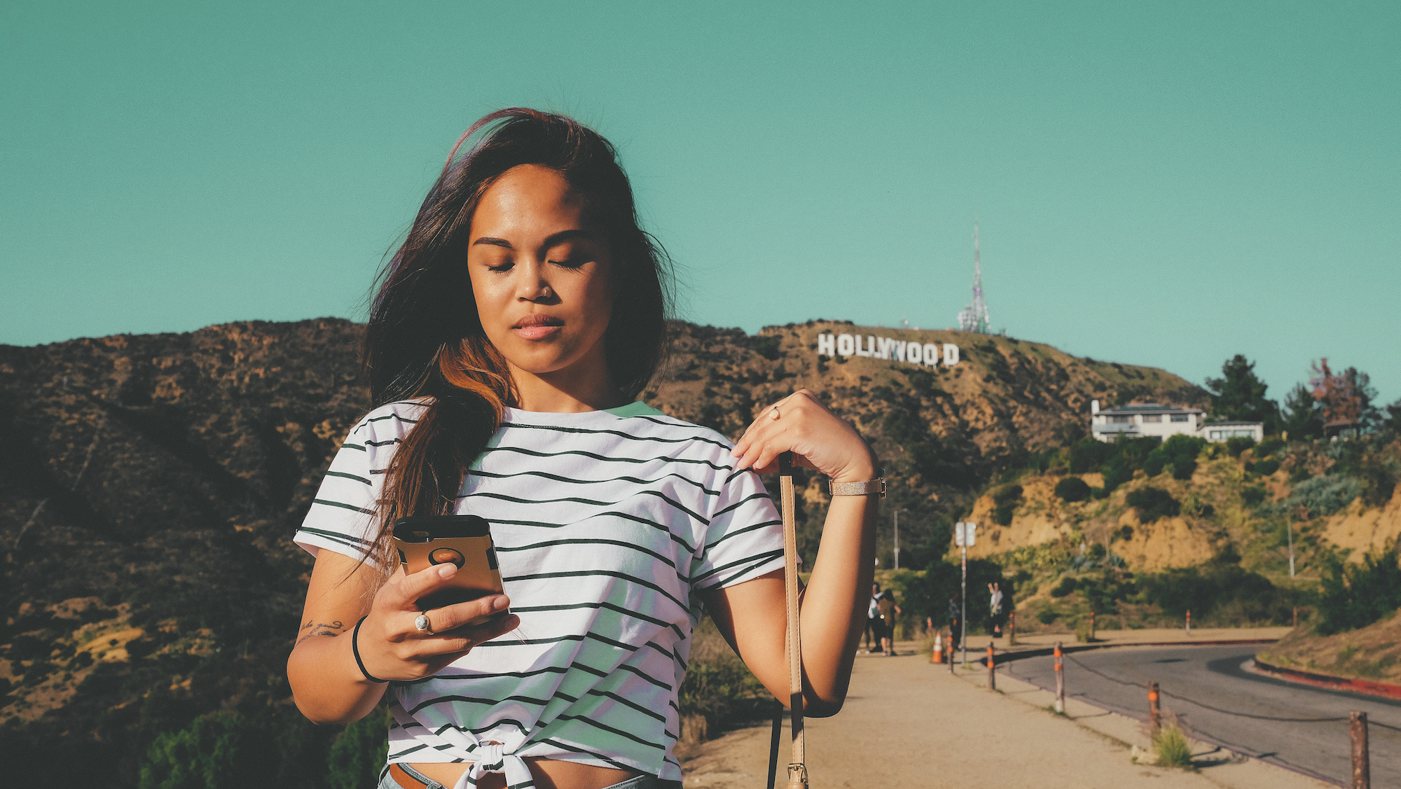 Therapy for Entrepreneurs and Business Owners - a woman in a striped shirt walking outside while looking at her phone