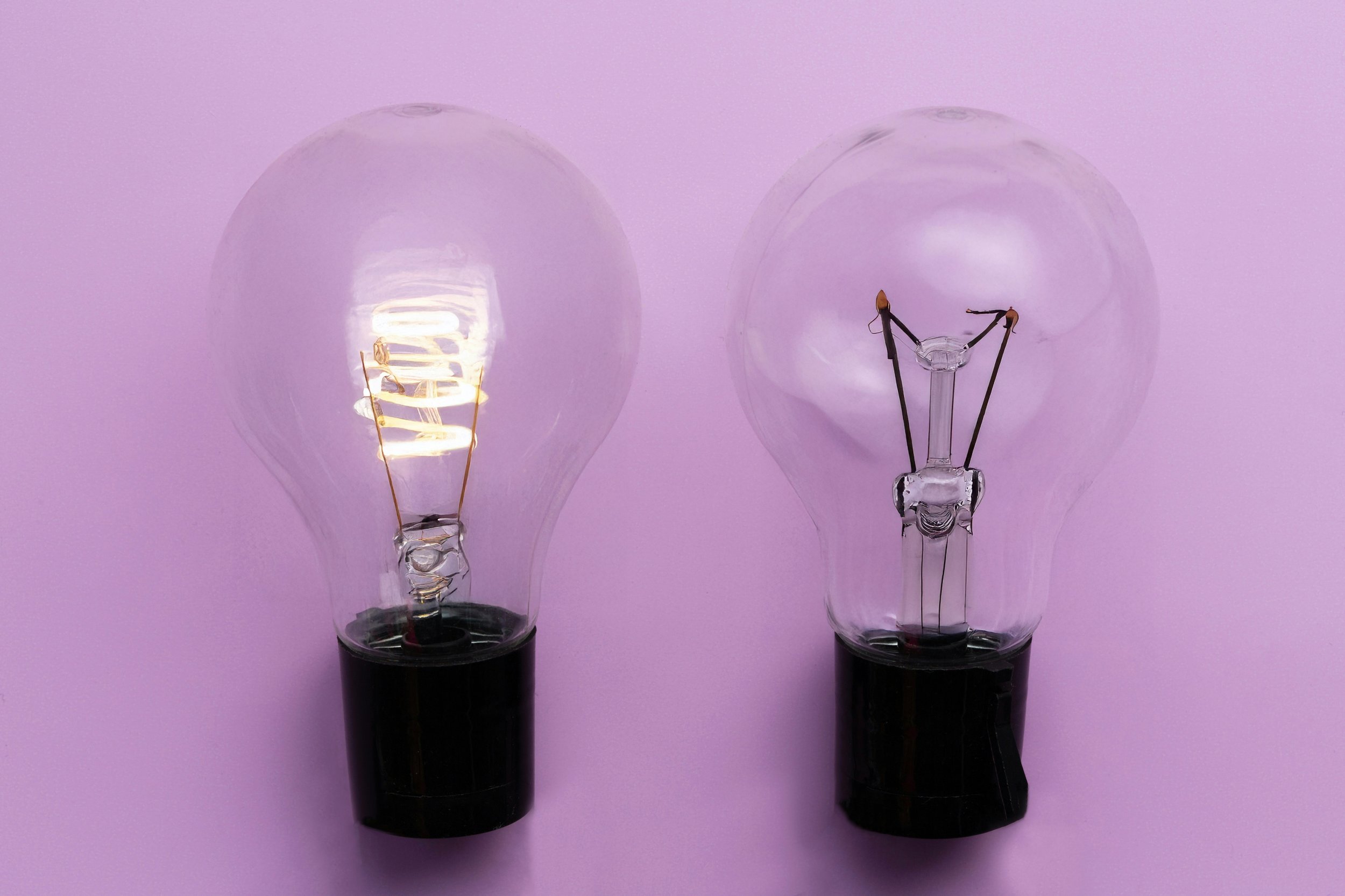 Two lightbulbs, one on and one off, symbolizing the dimming effect that burnout can have on people