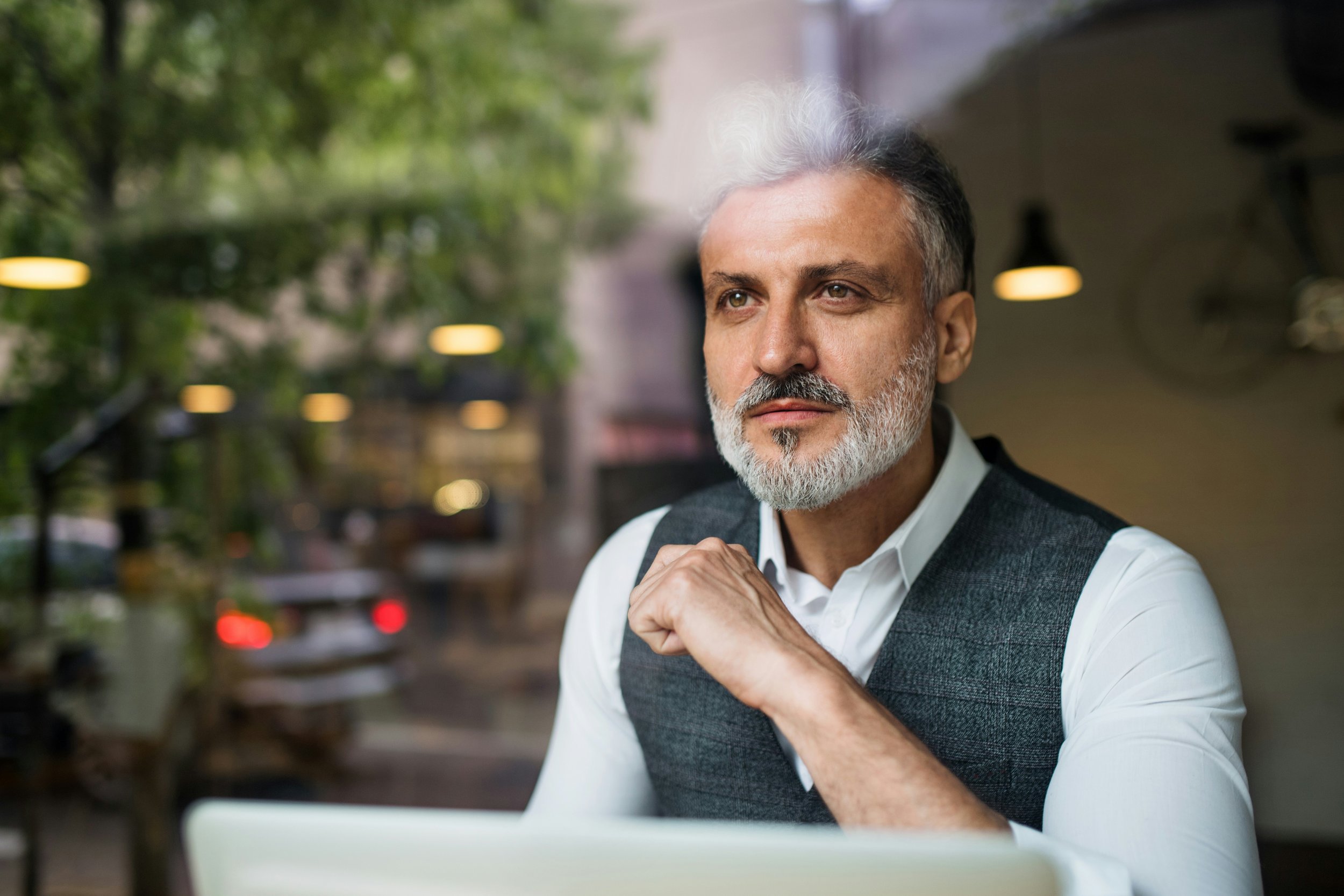 Older professional man sitting in a cafe looking out the window