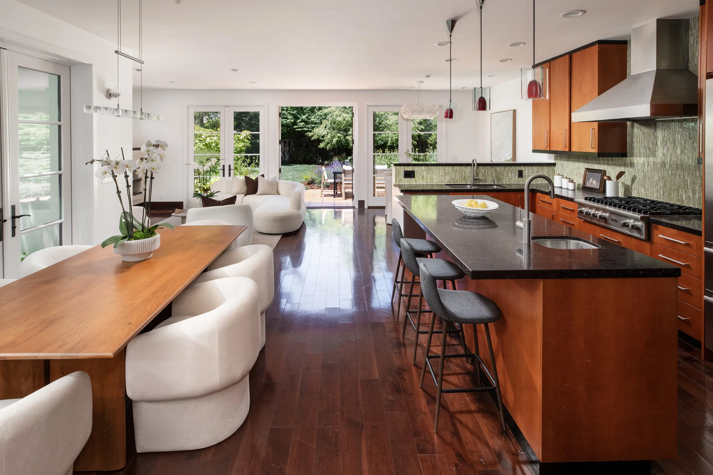 Open-concept kitchen and living room with large windows and glass doors leading to a backyard patio.