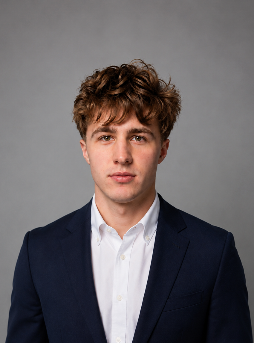 Professional headshot of Tyler Stewart, President of Operations at TG Talent Team LLC, in a dark blue blazer and white collared shirt against a gray background.
