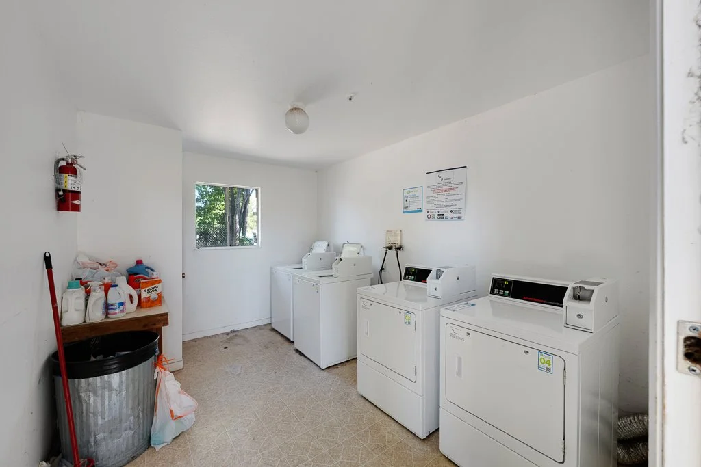 Laundry room with three washing machines and a laundry detergent station.