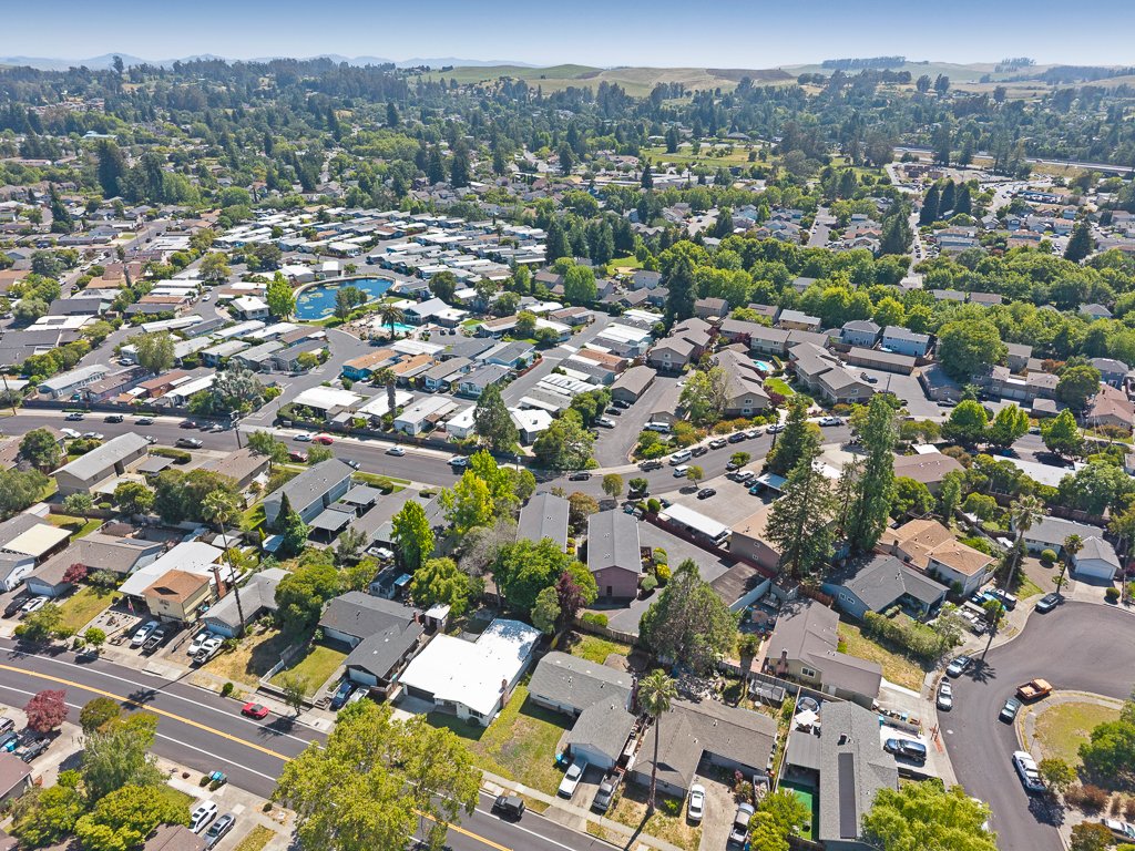 Aerial view of a suburban neighborhood with single-family homes, streets, and a community pool in the center.