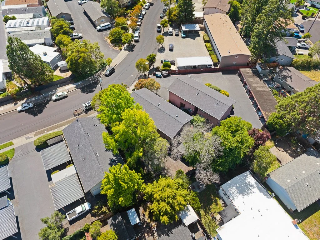 Aerial view of a residential neighborhood with houses, trees, and parked cars along the streets and in driveways.