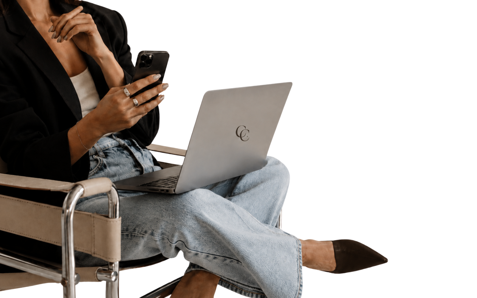 Person sitting in a wheelchair with a laptop on their lap, holding a smartphone in their hand.