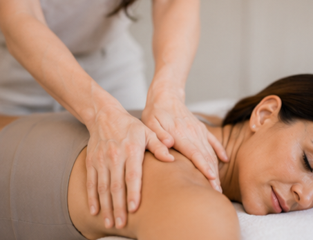 A woman receiving a massage on her shoulder from a massage therapist.