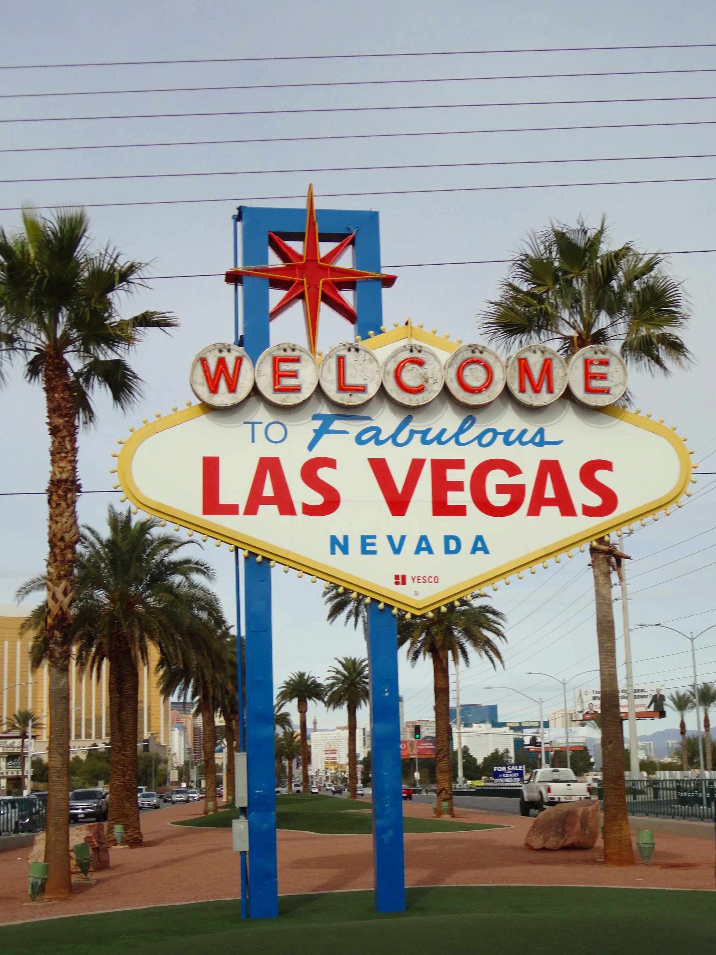 Welcome sign in Las Vegas, Nevada, with palm trees and city buildings in the background.