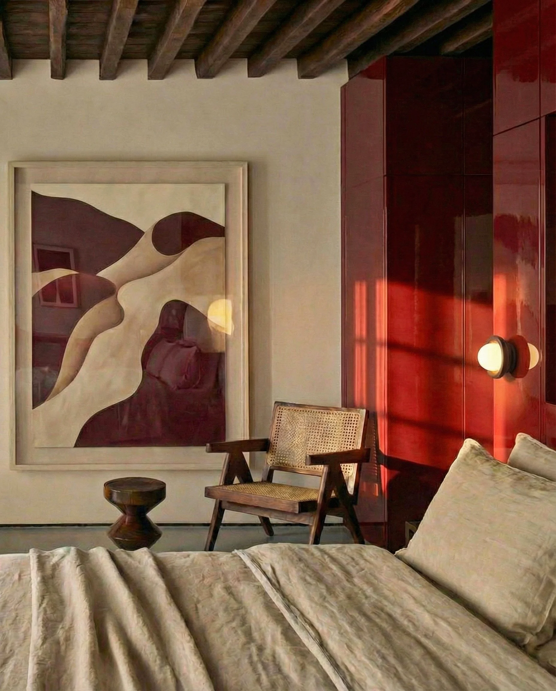 Een interieur met een houten plafond, een abstract kunstwerk en diverse meubels, waaronder een stoel en een tafel, in een warme sfeer.