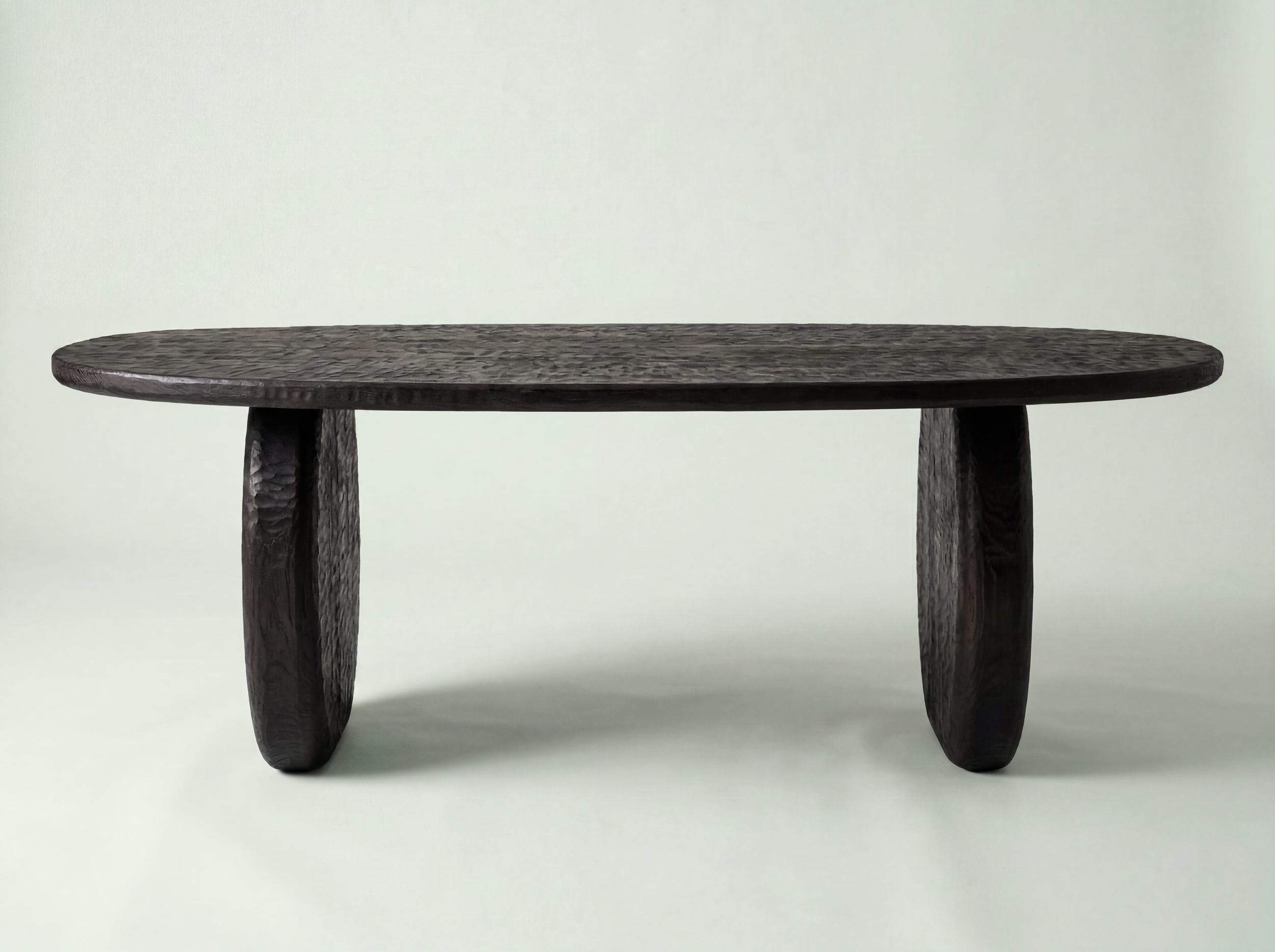 Ronde, donkere houten tafel met een getextureerd oppervlak en drie stevige poten, geplaatst op een lichte achtergrond.