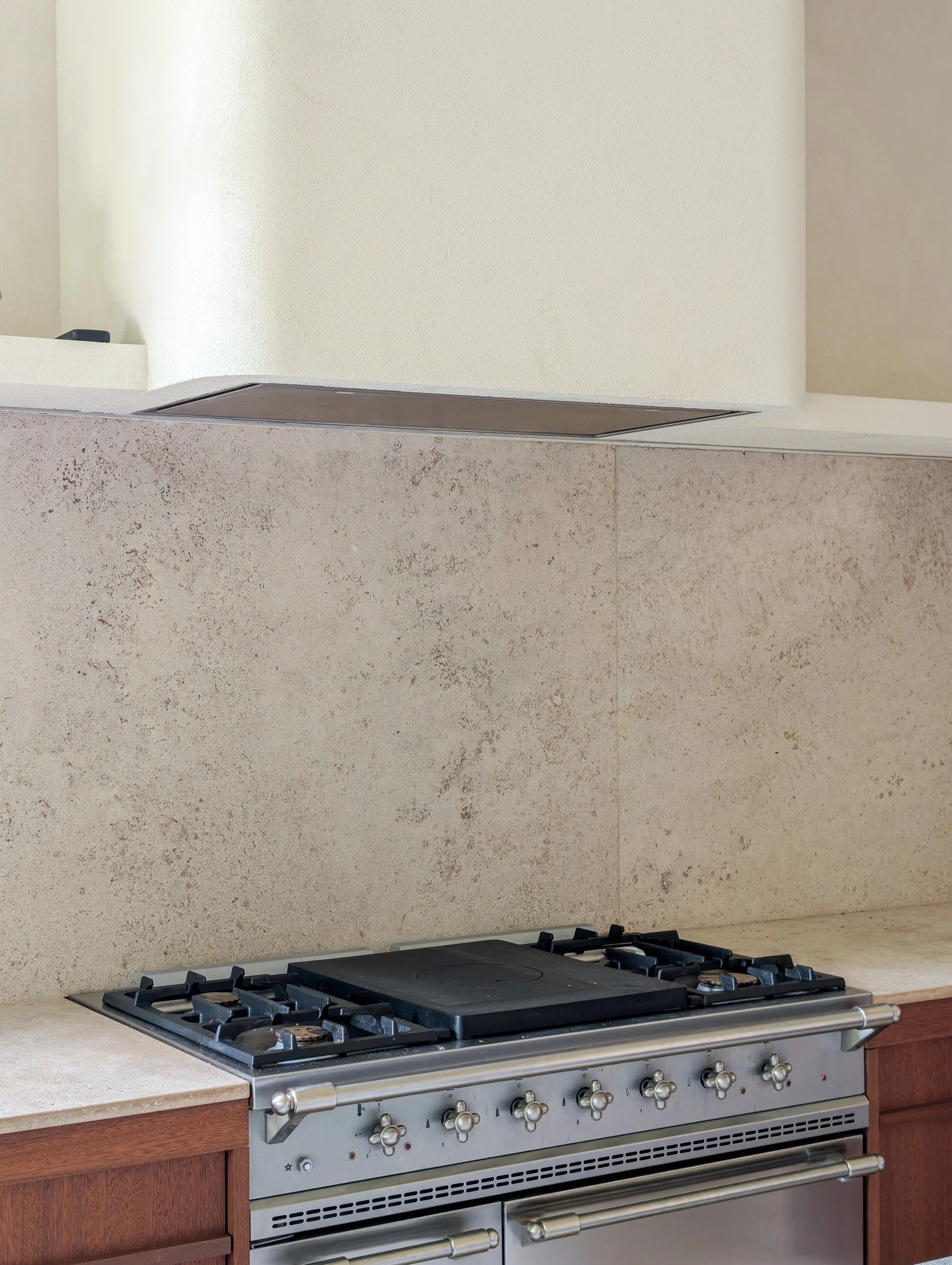 Een moderne keuken met een fornuis en een beige tegelachtergrond.