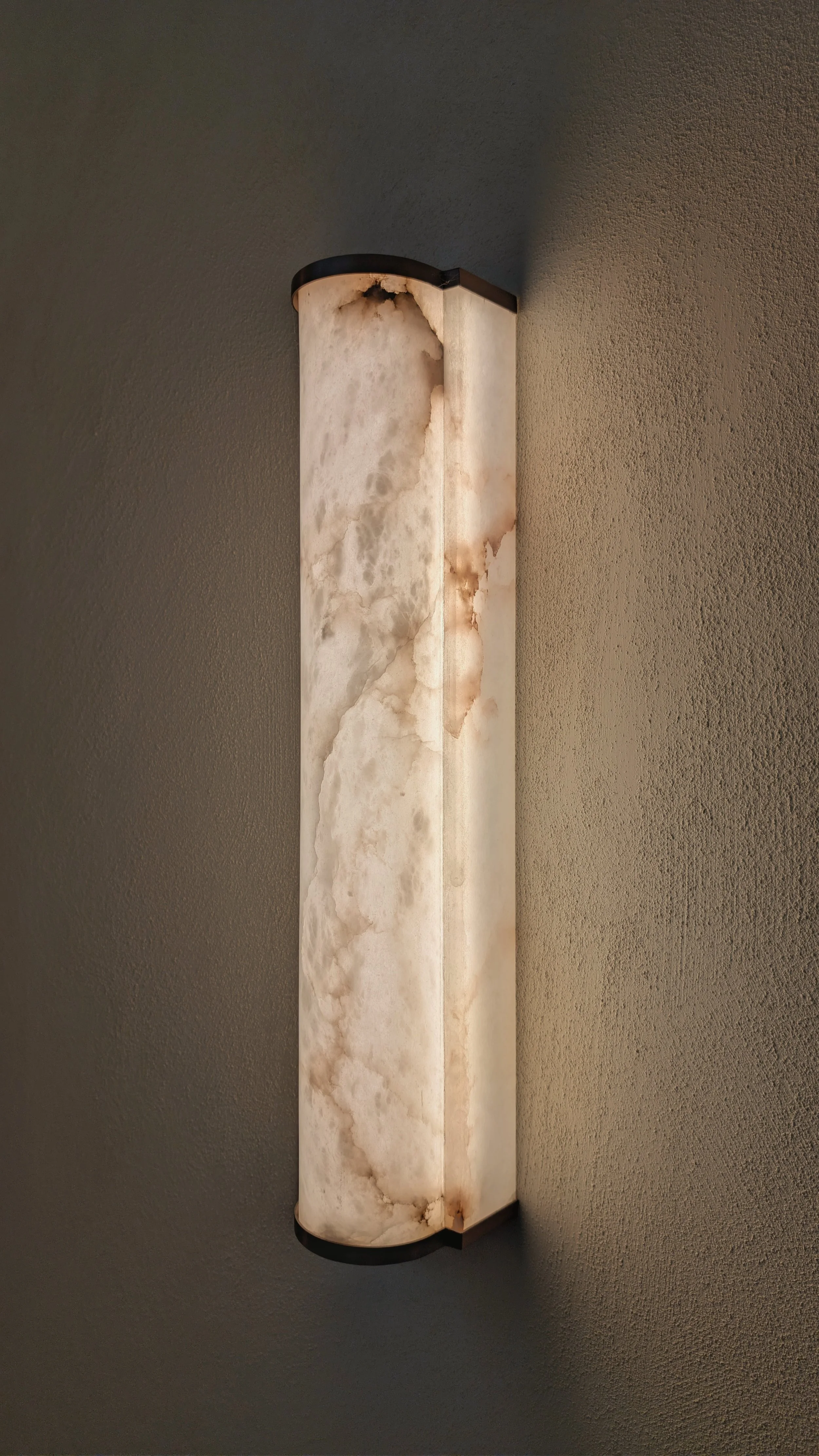 Een kapotte en vlekkerige plafondlamp tegen een effen muur.