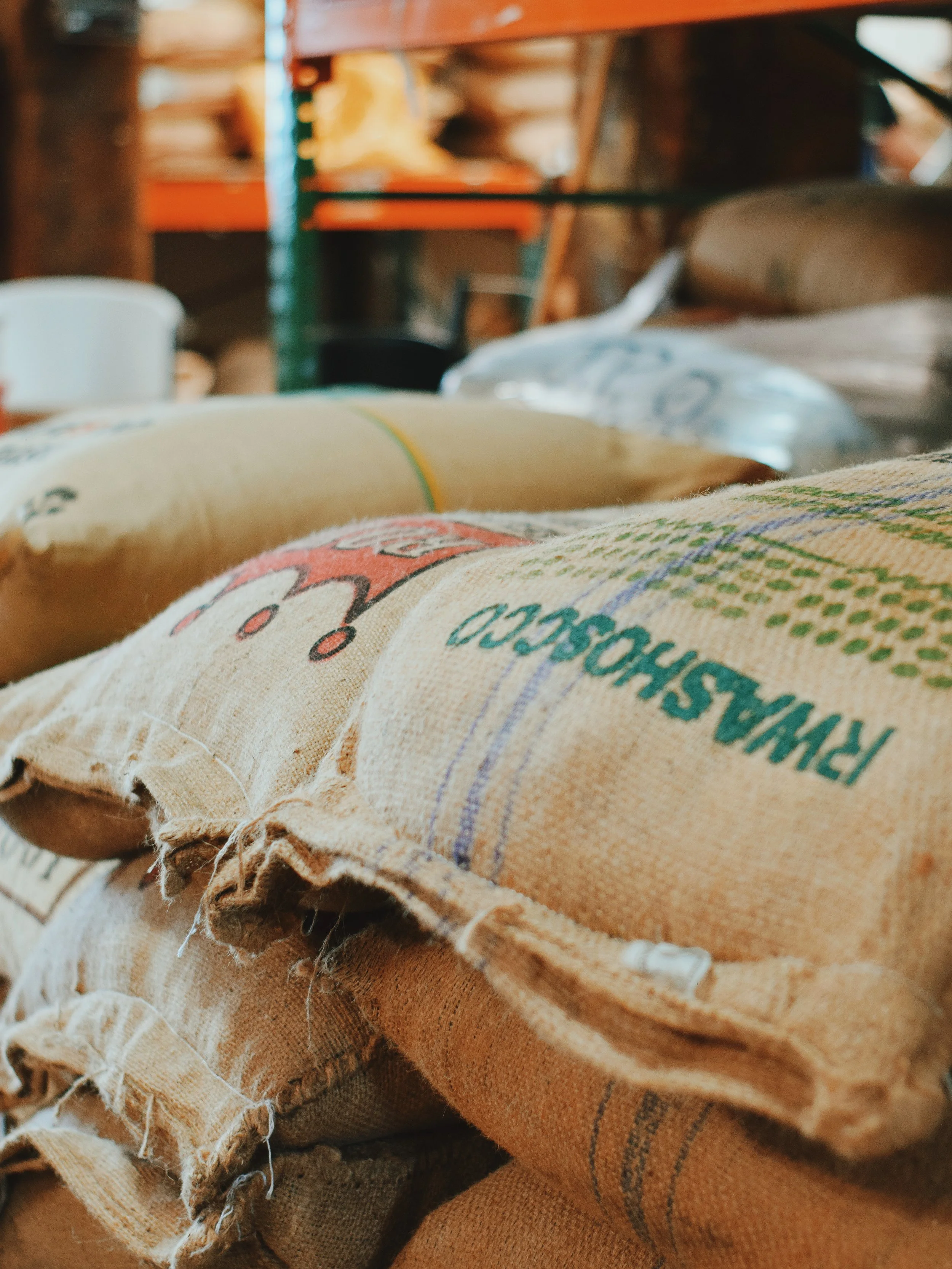 Burlap bags of green, unroasted coffee are stacked in a coffee roastery