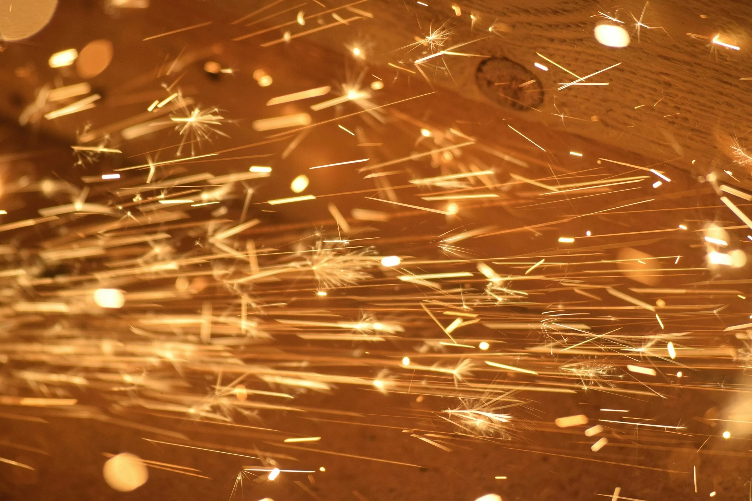 Close-up of sparks flying against a dark background, likely from grinding or cutting metal.