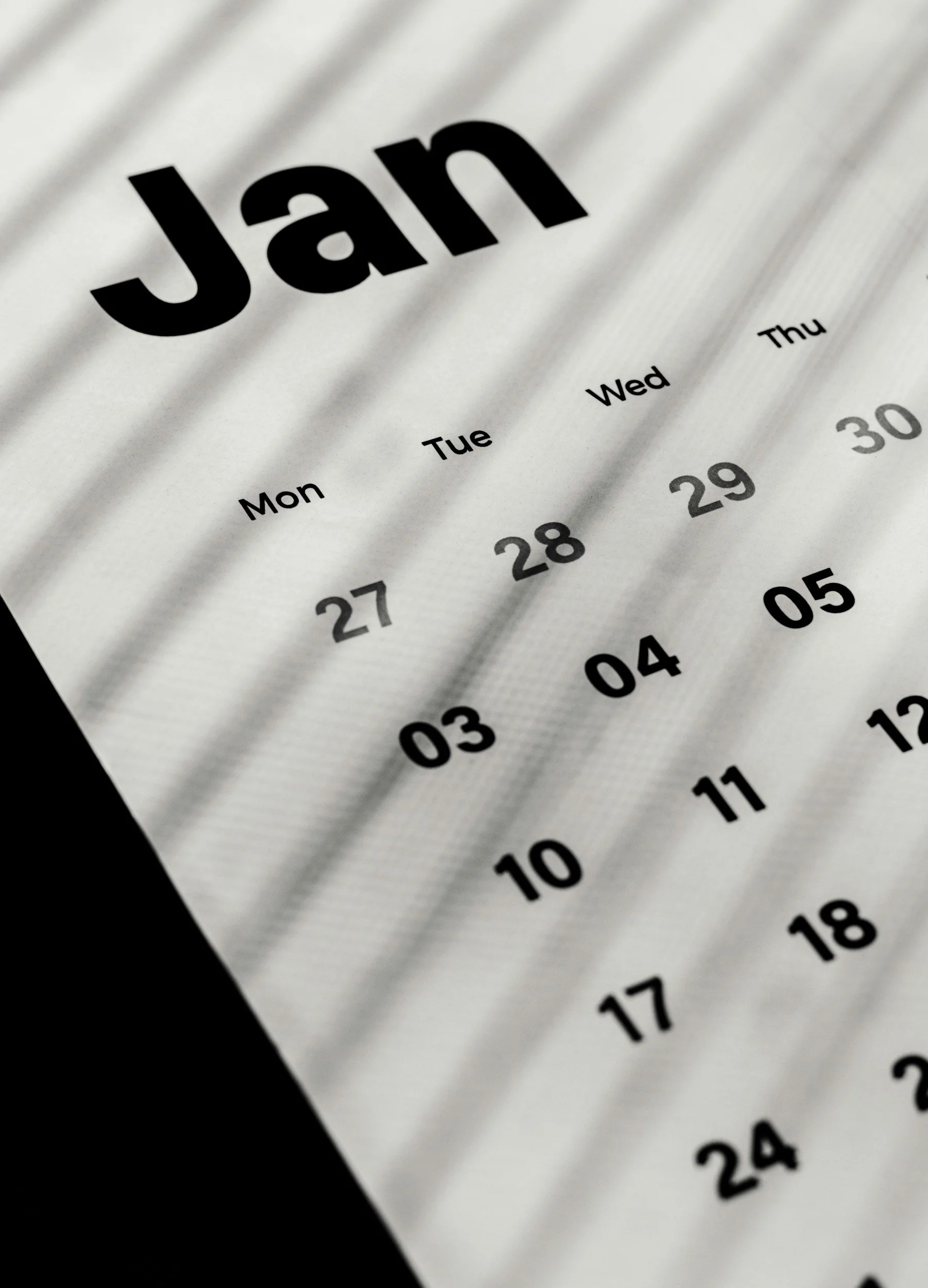 Close-up of a calendar showing the month of January with the dates and days of the week in black text on a white background.