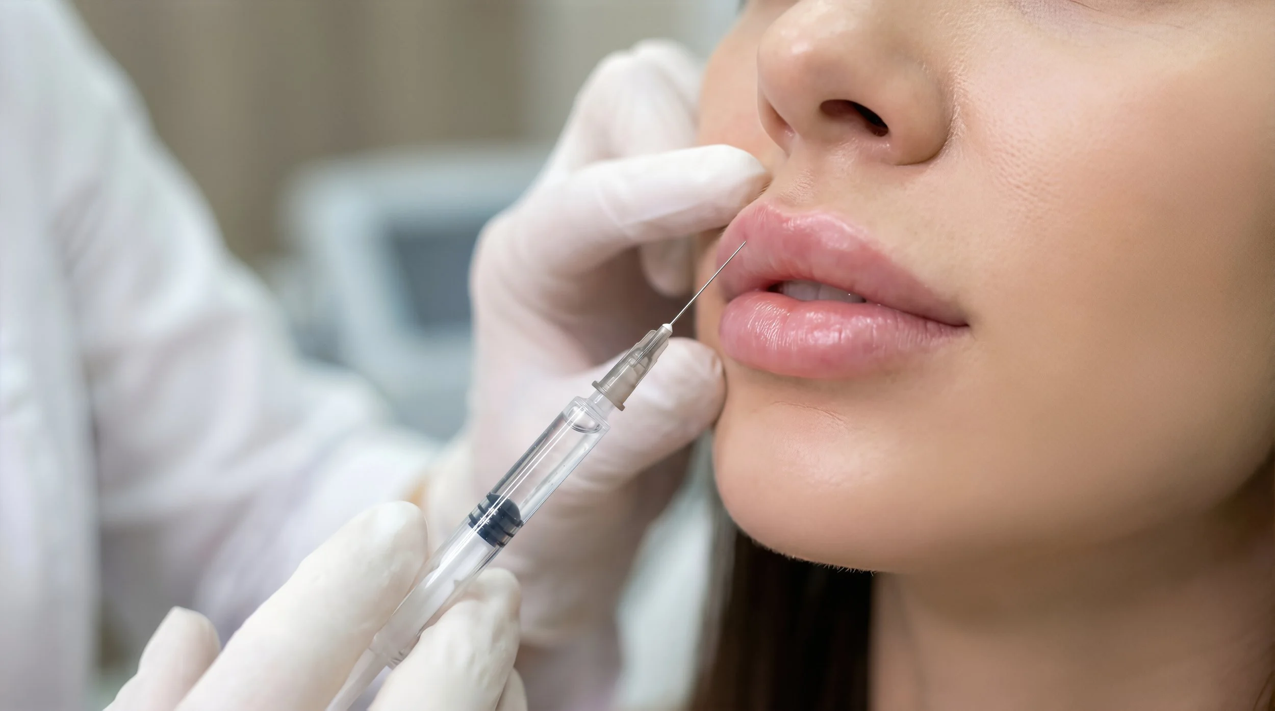 Close-up of a woman receiving a cosmetic treatment with a syringe by a medical professional wearing white gloves.
