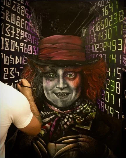 A person is painting a portrait of a woman with wild red hair, wearing a large pink hat and a patterned scarf. The background displays glowing numbers and data, suggesting a digital or technological theme.