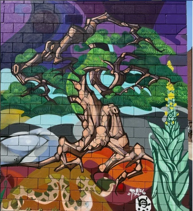 Colorful mural of a twisted, leafy tree in a pot, with various vibrant background colors and patterns.