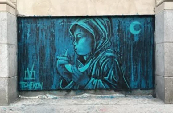 Blue graffiti mural of a young girl with a hood, holding a small object, with a moon in the background.