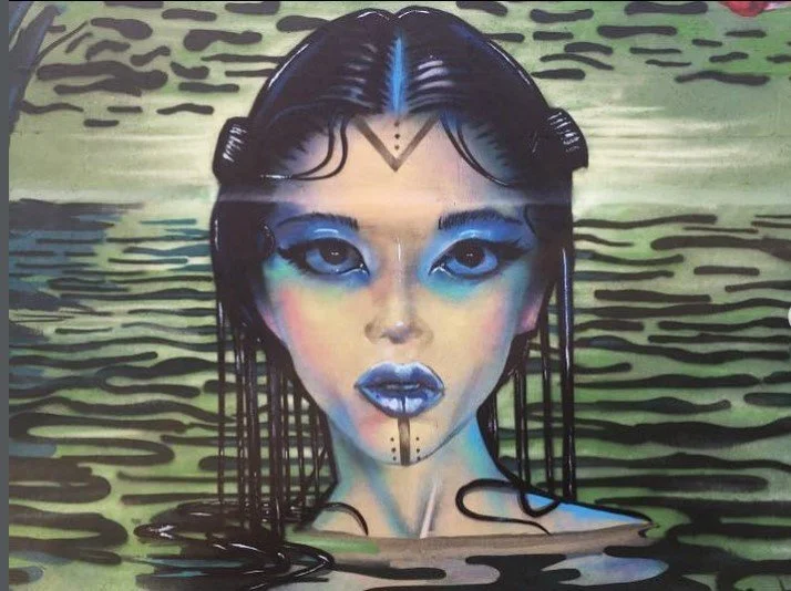 Artistic painting of a woman with dark hair and blue makeup, submerged in water with her face visible above the surface, behind a textured green background. Art, street art, painter, mural, graffiti, spray paint, oil paint, montreal, commission, Futu