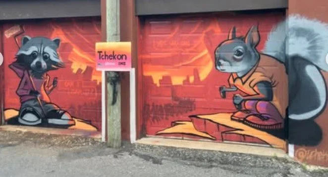 Graffiti mural of a raccoon and a squirrel sitting on a cityscape background with fiery sky, painted on a garage door. Art, street art, painter, mural, graffiti, spray paint, oil paint, montreal, commission, Futurism, retro Futurism, cyber punk, punk