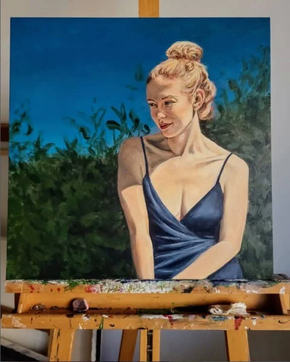 Painting of a woman with blonde hair tied in a bun, wearing a dark blue dress, in front of a green foliage background under a blue sky.