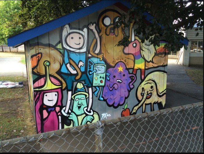 Colorful mural of cartoon characters, including a smiling girl with pink hair, a green character with a backpack, a dog, a unicorn, an egg, and other whimsical creatures on a shed with a blue roof.