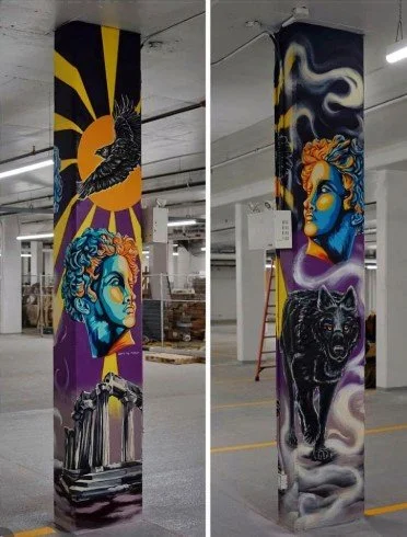 Colorful mural on two pillars depicting a sun with a bird, a woman's face with blue skin, a lion, and ancient ruins, all in a vibrant, artistic style.