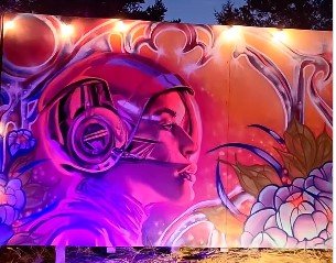 Colorful graffiti mural of a woman's face with headphones and floral elements in vibrant pink, purple, and orange hues.