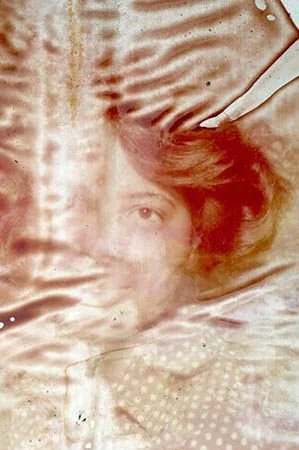A layered, abstract image with a woman’s face, textures, and patterns blending with metallic and fabric-like elements.