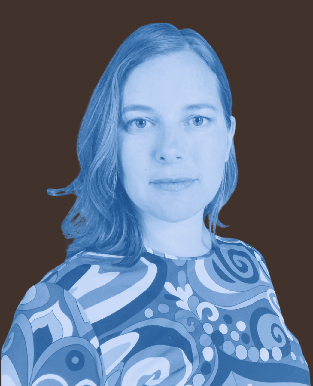 Portrait of a woman with shoulder-length hair, wearing a patterned top with swirls and floral designs, against a plain dark background.