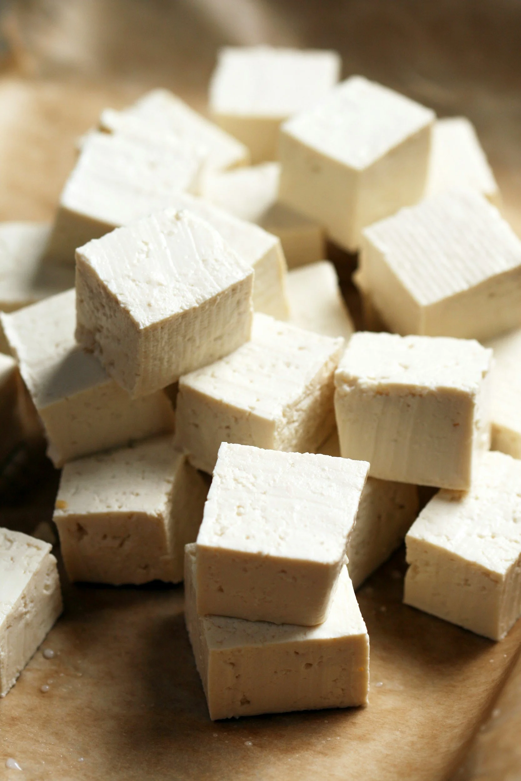 Close-up of white cubes of tofu on parchment paper.
