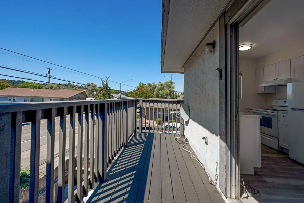 Balcony with a view of the neighborhood, kitchen visible from the balcony, and a satellite dish attached to the wall.