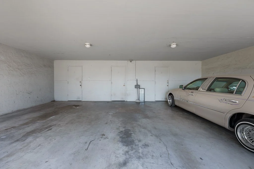 Empty underground parking garage with one vintage beige car parked on the right side.
