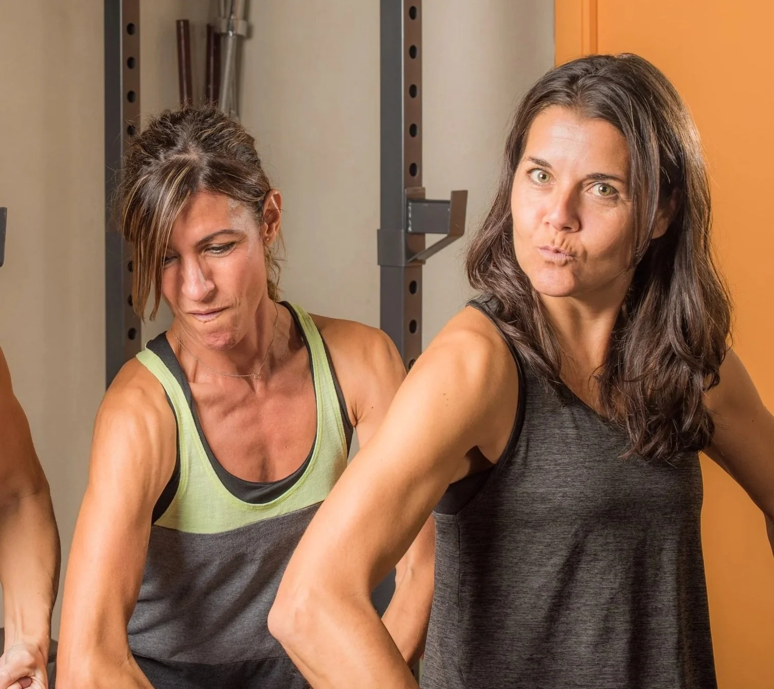 Two women in workout clothes striking playful poses in a gym.
