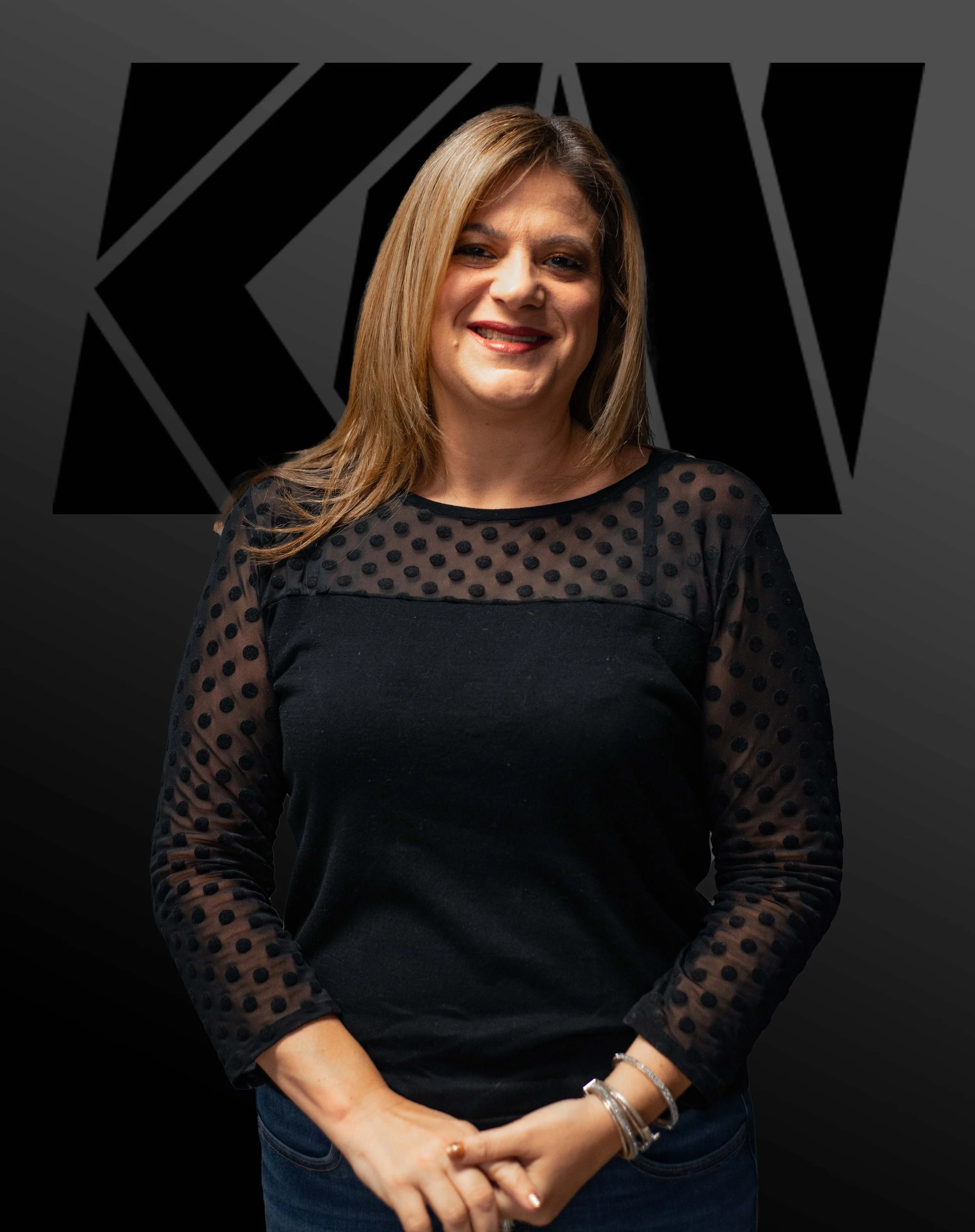 A woman with shoulder-length light brown hair smiling in front of a dark background with the large 'KIA' logo.