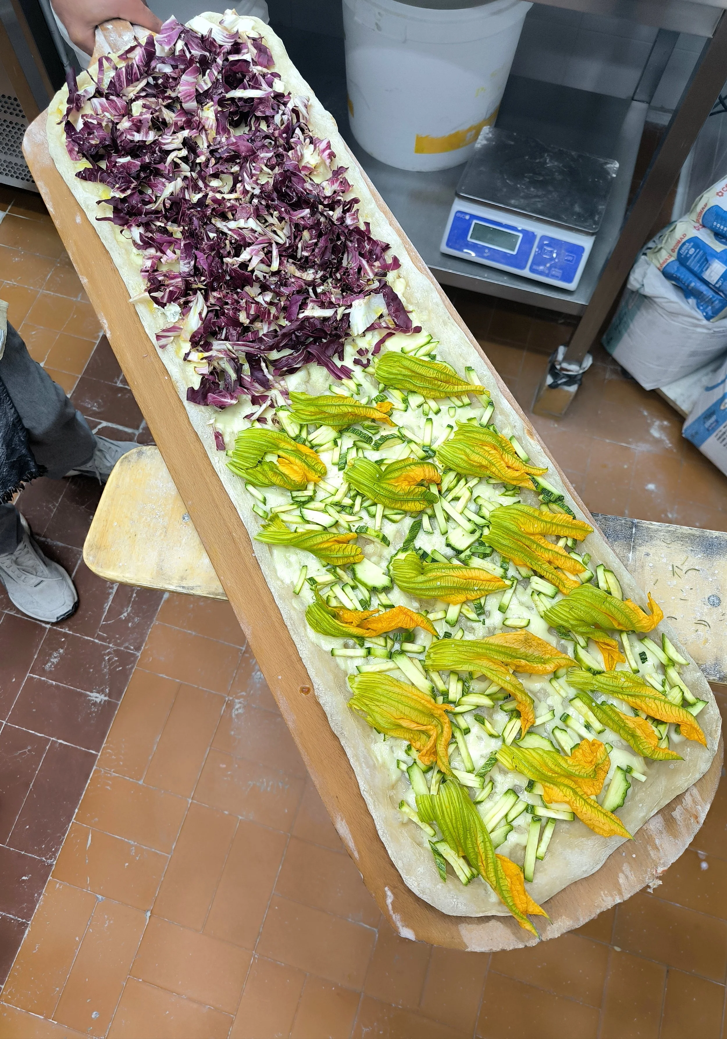 Fiori di zucca ripieni di formaggio e verdure su un grande tavolo di cucina.