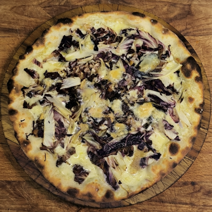 Pizza con crema, porri, e radicchio su una teglia di legno.