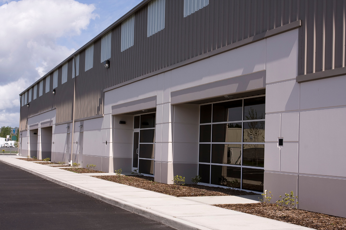 Commercial building with large glass windows, metal siding, and empty parking lot.