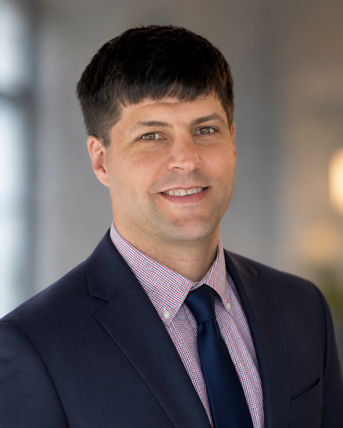 A professional man in a suit smiling at the camera in an indoor setting.